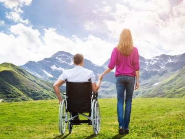 A man in a wheelchair and his female companion enjoy the magnificent mountain panorama.