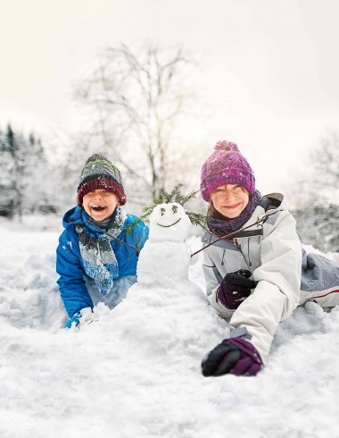 Kinder mit Schneemann lachend