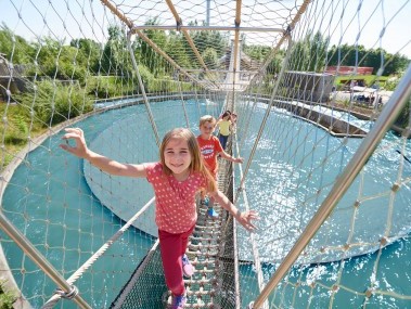 Kinder laufen im Stahlgehege über dem Wasser