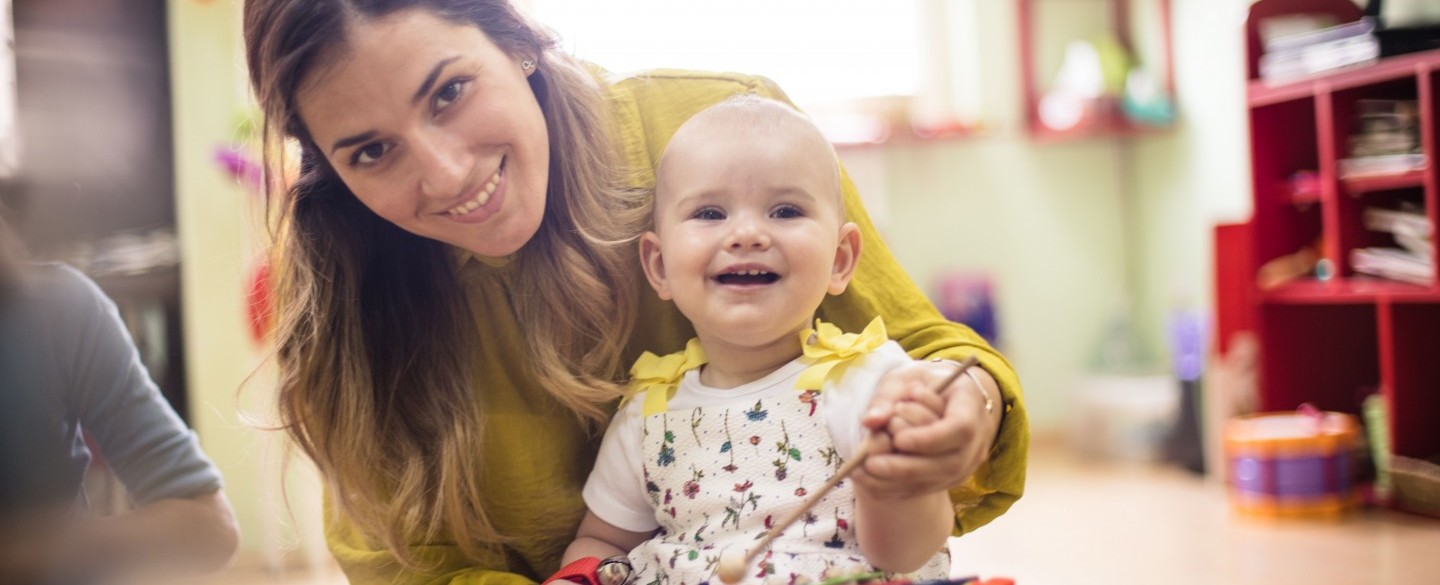 Baby mit Betreuungsperson am Malen