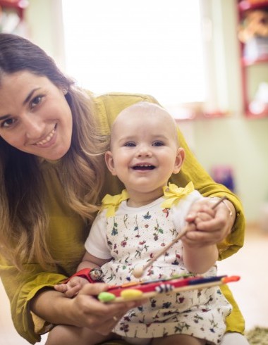 Baby mit Betreuungsperson am Malen