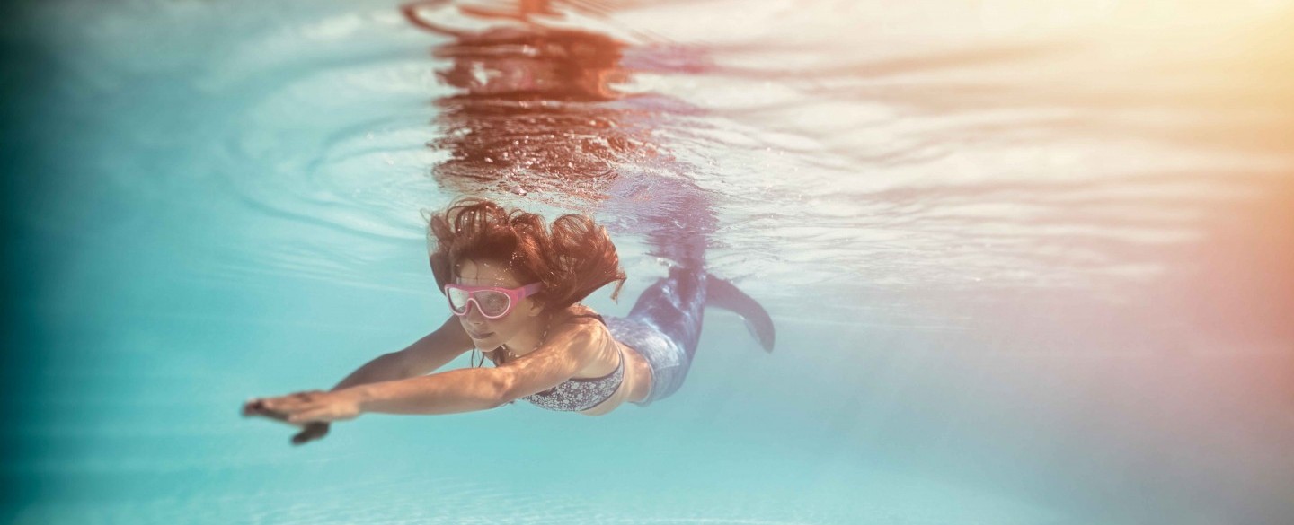 Kind mit Meerjungfrau-Kostüm am Schwimmen