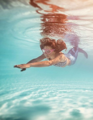Kind mit Meerjungfrau-Kostüm am Schwimmen