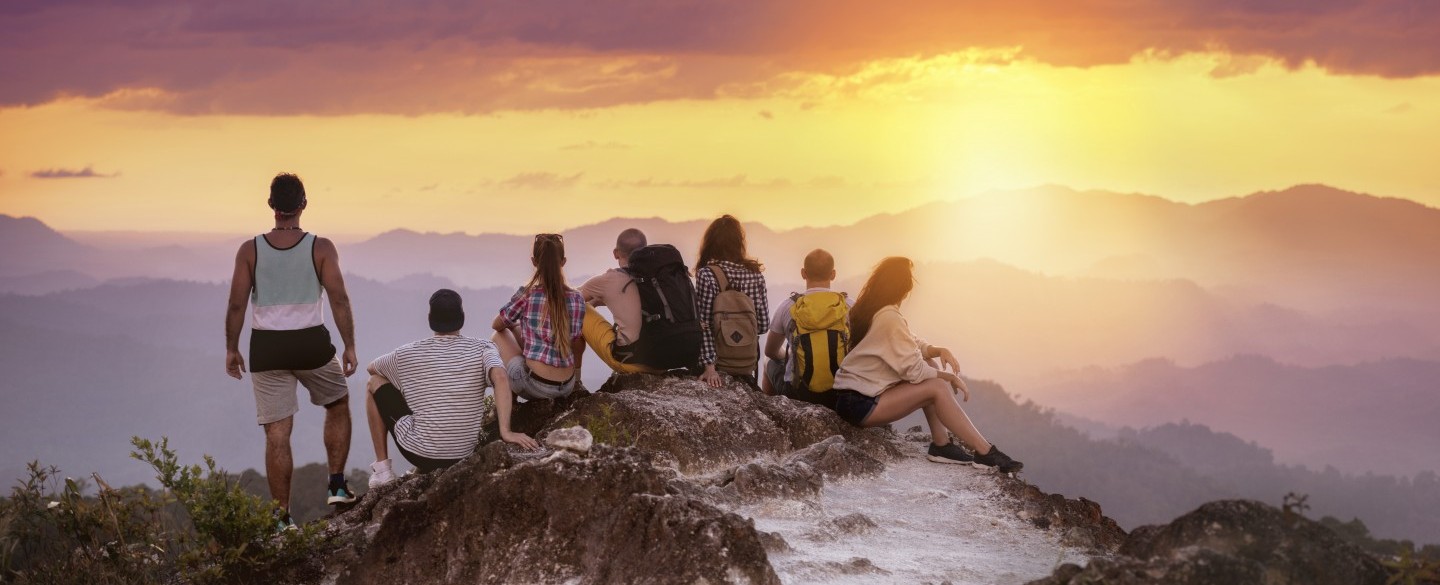 The whole tour group has reached the top of the mountain and marvels at the sunset