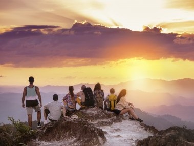 The whole tour group has reached the top of the mountain and marvels at the sunset