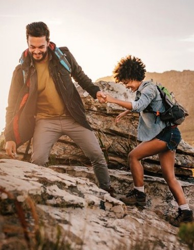 Paar am Wandern und Mann hilft Frau beim Wandern